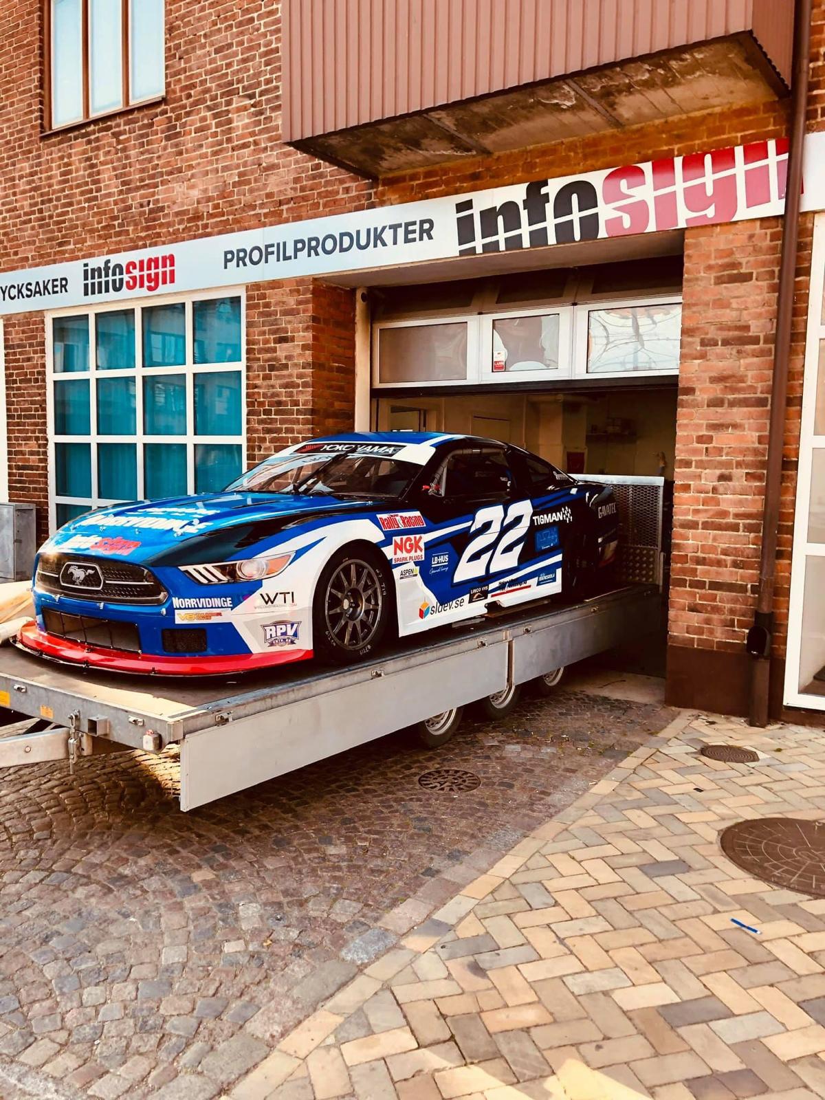 Racerbil med helfolerad vinyldekor framför Infosigns verkstad